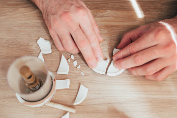 A man sequentially glues pieces of broken dishes - the task is to restore broken ceramics
