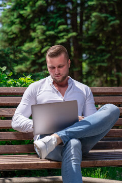 a man of European appearance works remotely using a laptop while he is in the park