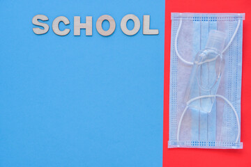 Study flatly. Education process after coronovirus with medical mask and sanitizer on blue and red background,back to school or kindergarten. summertime and learn. Woody school inscription, banner.