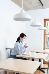 マスクをしながらお茶を飲んでいる女性
