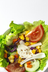 Fresh lettuce salad with tomatoes, red onion, corn, carrots, cucumber