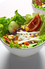 Fresh lettuce salad with tomatoes, red onion, corn, carrots, cucumber