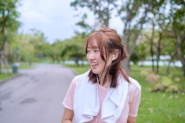 A beautiful young Asian woman in early 20s is running and having fun with her friend in a public park.