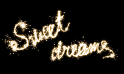 The inscription Sweet dreames on a black background with sparklers using a simulated long exposure.