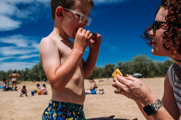 close up of mother giving son a snack on the beach