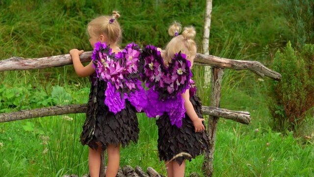 Photographer takes pictures of beautiful girls playing violet butterflies. Girls with butterfly wings are standing on the wooden bridge outdoors