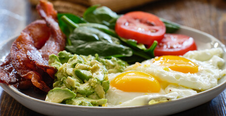 keto breakfast plate with eggs bacon and mashed avocado