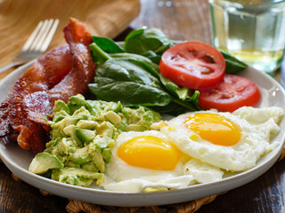 keto breakfast plate with eggs bacon and mashed avocado