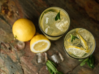 Fresh lemonade cooking with ice, mint and lemon by barista hands on table bar background.