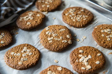 Freshly baked homemade oatmeal cookies on baking tray on white kitchen table.