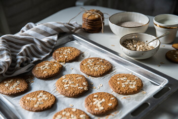 Freshly baked homemade oatmeal cookies on baking tray on white kitchen table.