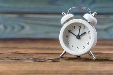 White alarm clock on a wooden background. Concept of time, awakening, copy space.