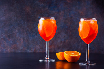 Aperol spritz cocktail on dark background. Two glasses of aperol spritz with orange slised. Summer cocktail in glass. Copy space