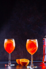 Aperol spritz cocktail on dark background. Two glasses of aperol spritz with orange slised. Summer cocktail in glass. Copy space