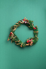Christmas wreath on green background. New year composition. Top view, flat lay. Copy space. Decor for Christmas celebration. Greeting card, minimal concept
