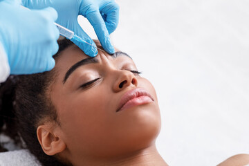 Young black woman receiving botox injection at beauty salon