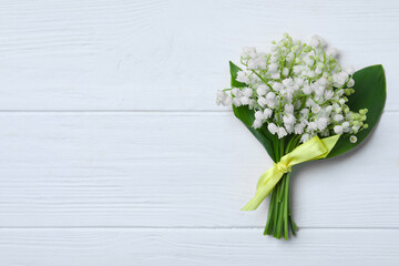 Beautiful lily of the valley flowers on white wooden table, top view. Space for text