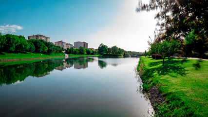 Fototapeta na wymiar Scenic view natural park. Eskisehir, Turkey. The river flowing through the city. Reflections on the water. Colorful landscape. Sunny and windy day. Long exposure.