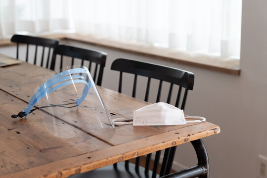 木のテーブルにマスクとフェイスシールドが置いてある