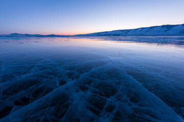 Early morning on the ice of lake Baikal against the background of mountains and ice