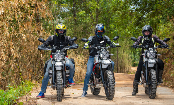 three friends riding their scrambler motorcycles through forrest