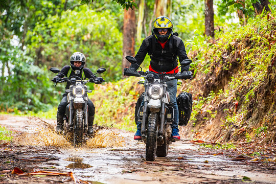 two friends riding their scrambler motorcycles through forrest