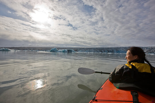 woman rowing sea kayak on J&circ;kuls&middot;rl&Ucirc;n glacier lagoon in Iceland