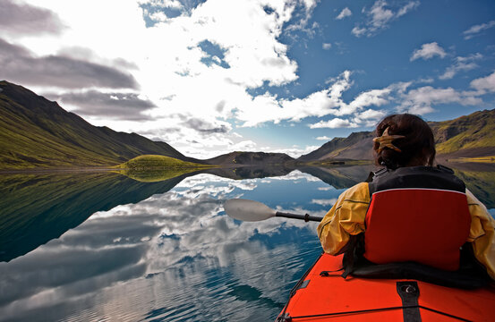 woman rowing sea kayak on still lake in central Iceland