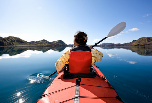 woman rowing sea kayak on still lake in central Iceland
