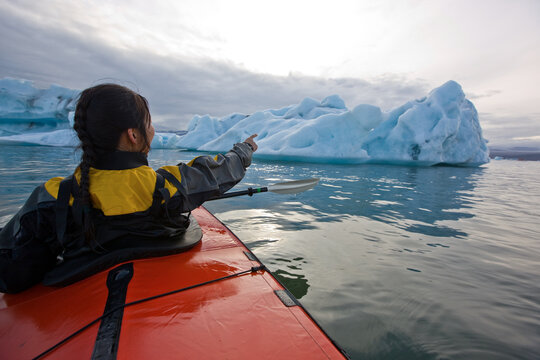 woman rowing sea kayak on J&circ;kuls&middot;rl&Ucirc;n glacier lagoon in Iceland