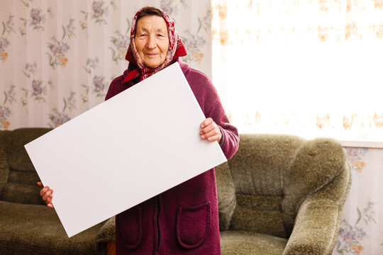 elderly woman holding a blank vertical canvas in her hands. Empty frame for text or photo. woman with mockup poster