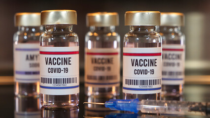 Covid-19 vaccines defocused effect and syringe on black table
