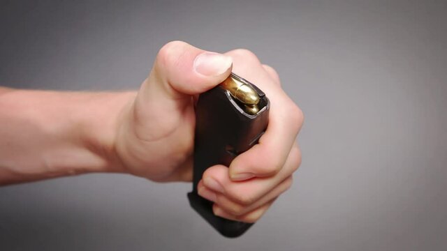 Man loading pistol cartridges into polymer magazine