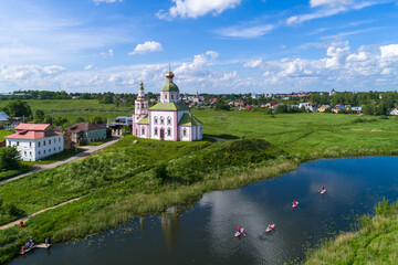 Fototapeta na wymiar Suzdal, Russia. Tourists traveling on SUP boards along the Suzdal River.