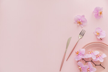 Flower and table settings overhead composition on light pink background. Pink ceramic plates,...