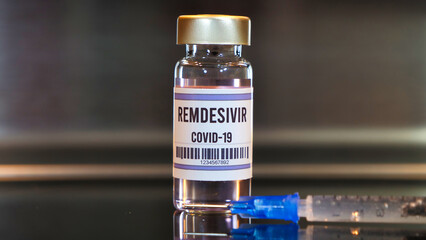 Remdesivir drug and syringe on black table