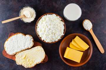 Dairy products. Milk, cottage cheese, hard cheese and sour cream on a dark background. Bread with cream cheese on a black background. Top view