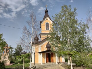 Fototapeta na wymiar Old orthodox church of yellow color. White birch trees. Blue sky with olaks. Tsypovo. Moldova