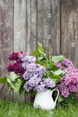 Beautiful spring flowers. purple lilac in white vase on wood old background