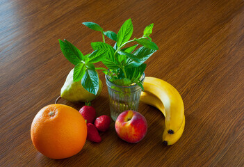 Mint in a glass and fruit on the table.
