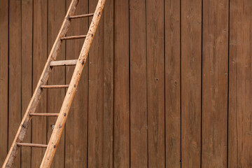 Old wooden ladder in front of wooden wall. Step ladder against a wall. Growth, future, development...