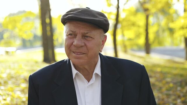Portrait of a fascinated senior man in a cap looking at one point in park