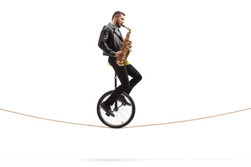 Musician riding a unicycle on a rope and playing a saxophone © Ljupco Smokovski