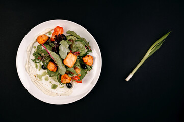 healthy tasty food on a white plate lies on a black background.