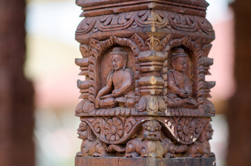 Buddha intertwined in the wood of a column, with oriental allegories.