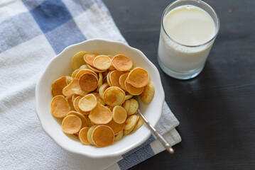 Tiny pancake cereal and milk on dark rustic background