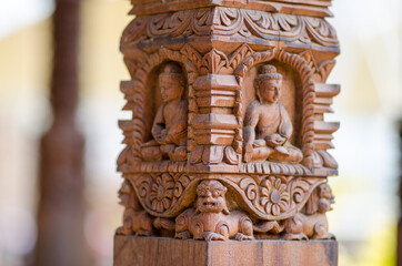Buddha intertwined in the wood of a column, with oriental allegories.