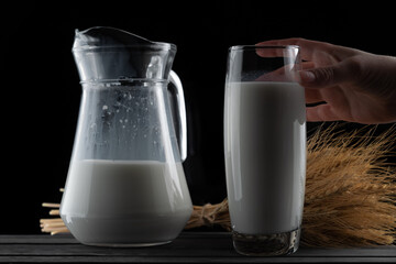 jug of milk and a glass on a black background