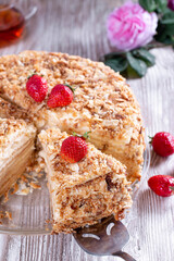 Piece of cake Napoleon on a plate, decorated with a red ripe strawberry