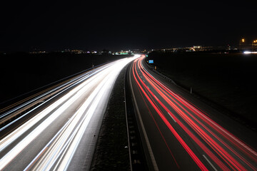 Obraz premium Highway light car trails leading from passing cars during night.